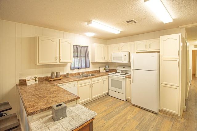 277 Lucy, Livingston, TX 77351 - kitchen with white appliances, a sink, a peninsula, light wood finished floors, and a textured ceiling
