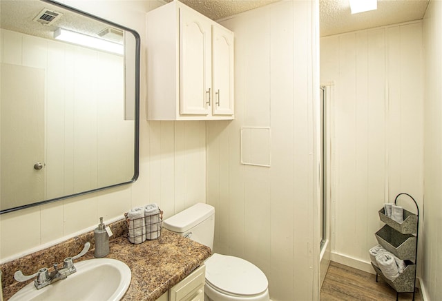 277 Lucy, Livingston, TX 77351 - full bath featuring a shower with shower door, vanity, toilet, wood finished floors, and a textured ceiling