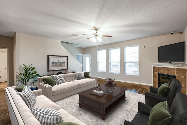 11019 Chestnut Path Way, Tomball, TX 77375 - living room with wood finished floors, a ceiling fan, a textured ceiling, a fireplace, and baseboards