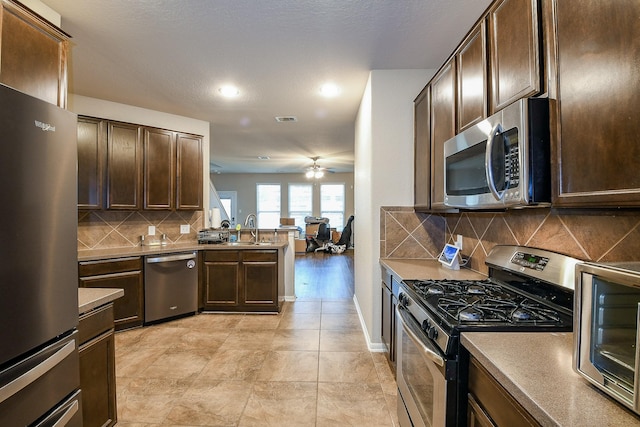 11019 Chestnut Path Way, Tomball, TX 77375 - kitchen featuring stainless steel appliances, a ceiling fan, a peninsula, a sink, and dark brown cabinets