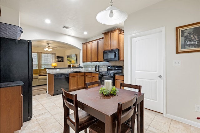 13610 Spectacled Bear Ln, Crosby, TX 77532 - kitchen with black appliances, a peninsula, light tile patterned floors, brown cabinetry, and a ceiling fan
