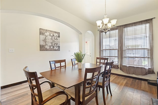 13610 Spectacled Bear Ln, Crosby, TX 77532 - dining area featuring a chandelier, light wood-style floors, arched walkways, and baseboards