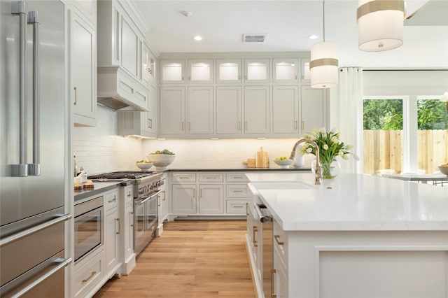 1611 Richelieu Ln, Houston, TX 77018 - kitchen featuring high quality appliances, light wood-style floors, recessed lighting, an island with sink, and tasteful backsplash
