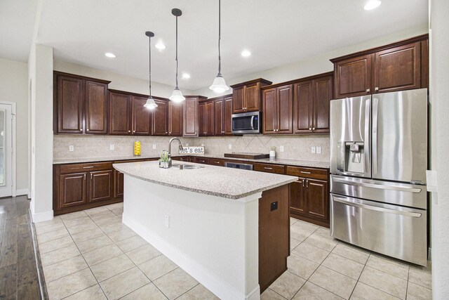 19903 Mulberry Pine Ln, Cypress, TX 77429 - kitchen with stainless steel appliances, a sink, dark brown cabinetry, decorative backsplash, and a center island with sink