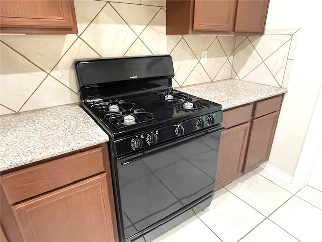 29314 Nectar Bloom Ct, Spring, TX 77386 - kitchen with black range with gas cooktop, backsplash, light stone counters, and light tile patterned flooring