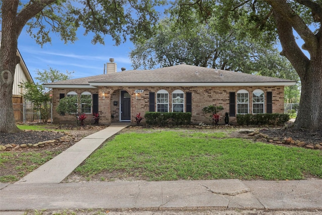 1008 N 30th St, Nederland, TX 77627 - view of front of house with a chimney, a front yard, brick siding, and roof with shingles