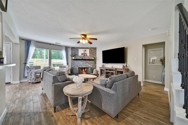 15314 Yellow Oak Trl, Cypress, TX 77433 - living room with a textured ceiling, baseboards, ceiling fan, a large fireplace, and wood finished floors