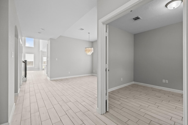 2302 Elmwood Trl, Katy, TX 77493 - empty room featuring light wood-style flooring, baseboards, a chandelier, and arched walkways