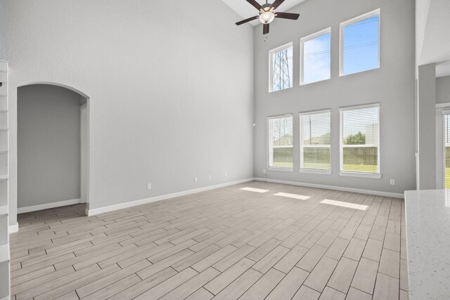 2302 Elmwood Trl, Katy, TX 77493 - unfurnished room with a towering ceiling, a ceiling fan, arched walkways, baseboards, and light wood-type flooring