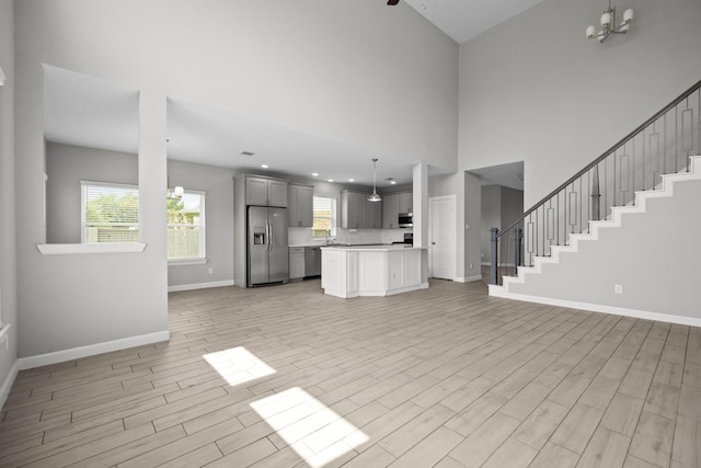 2302 Elmwood Trl, Katy, TX 77493 - unfurnished living room featuring baseboards, a chandelier, light wood finished floors, healthy amount of natural light, and a high ceiling