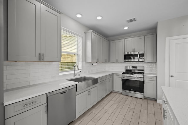 2302 Elmwood Trl, Katy, TX 77493 - kitchen with appliances with stainless steel finishes, a sink, gray cabinetry, light countertops, and decorative backsplash