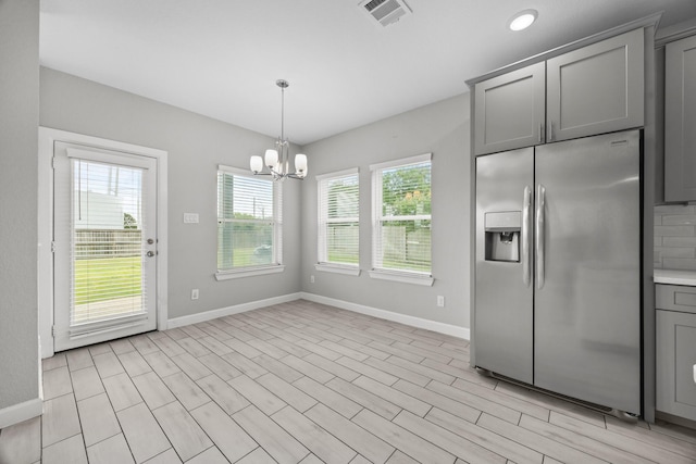 2302 Elmwood Trl, Katy, TX 77493 - kitchen with stainless steel refrigerator with ice dispenser, gray cabinets, baseboards, a chandelier, and light countertops