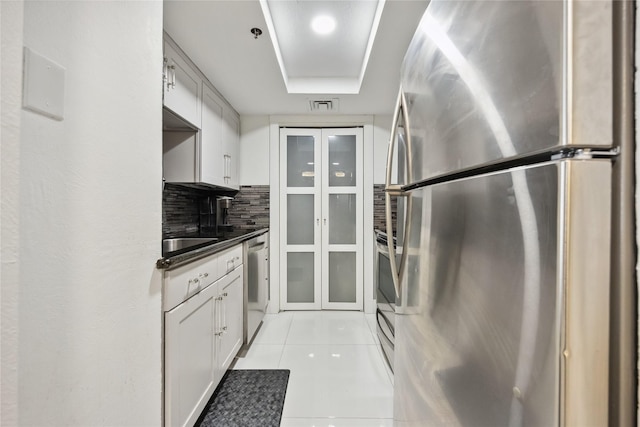 3525 Sage Rd Unit 1713, Houston, TX 77056 - kitchen with stainless steel appliances, light tile patterned flooring, dark countertops, decorative backsplash, and glass insert cabinets