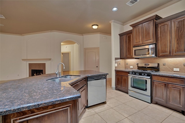 10 Tallgrass Way, Spring, TX 77389 - kitchen with appliances with stainless steel finishes, arched walkways, light tile patterned floors, backsplash, and crown molding