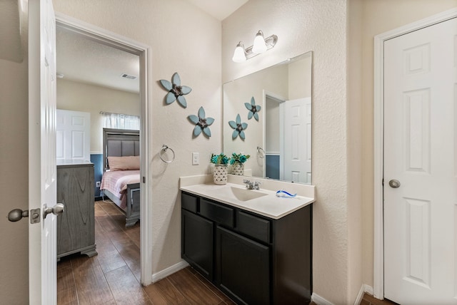 14706 Meadow Acre Trl, Houston, TX 77049 - bathroom with vanity, wood finished floors, ensuite bathroom, baseboards, and a textured wall