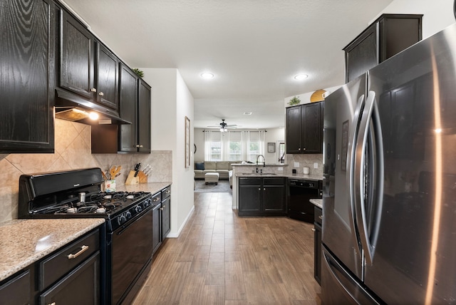 14706 Meadow Acre Trl, Houston, TX 77049 - kitchen featuring black appliances, a sink, under cabinet range hood, open floor plan, and wood finished floors