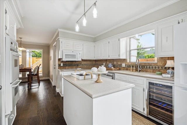706 St Ives Ct, Houston, TX 77079 - kitchen featuring wine cooler, white appliances, a sink, white cabinetry, and crown molding