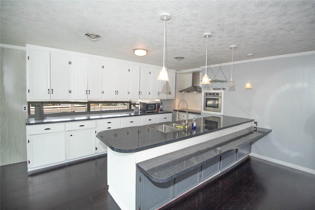 374 Harbor View Dr, Livingston, TX 77351 - kitchen featuring stainless steel appliances, a sink, dark countertops, wall chimney range hood, and a textured ceiling