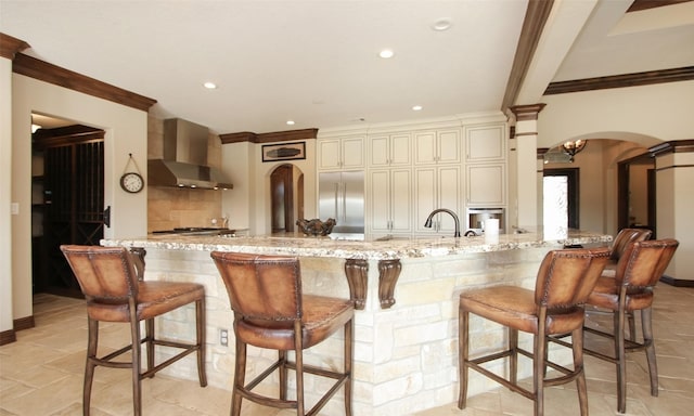 624 High Meadow Ranch Dr, Magnolia, TX 77355 - kitchen with wall chimney range hood, appliances with stainless steel finishes, arched walkways, ornate columns, and light stone counters