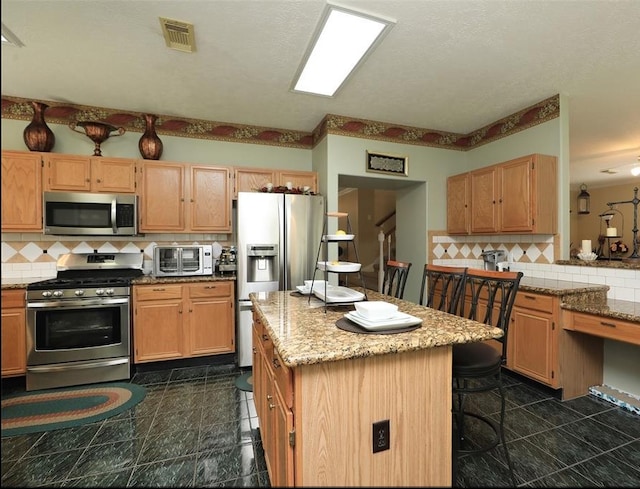 4915 Dove Springs Dr, Houston, TX 77066 - kitchen featuring stainless steel appliances, tasteful backsplash, light stone counters, a center island, and a breakfast bar