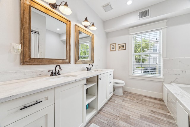 529 Fugate St, Houston, TX 77009 - bathroom with double vanity, baseboards, toilet, wood finished floors, and a bath