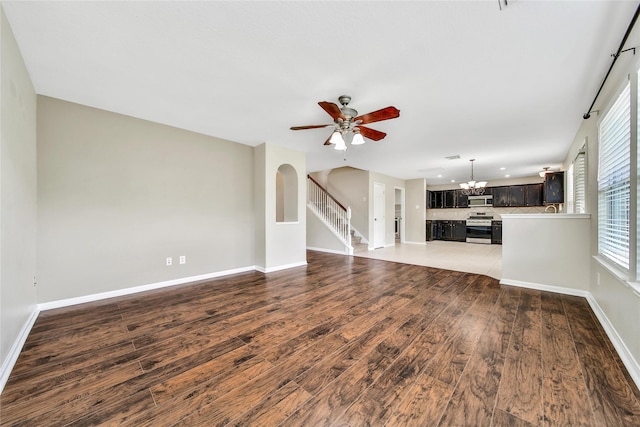 32126 Willow Creek Park, Conroe, TX 77385 - unfurnished living room featuring a chandelier, wood finished floors, a ceiling fan, stairway, and arched walkways