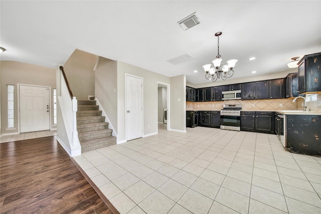 32126 Willow Creek Park, Conroe, TX 77385 - kitchen featuring stainless steel appliances, a chandelier, dark cabinets, backsplash, and light countertops
