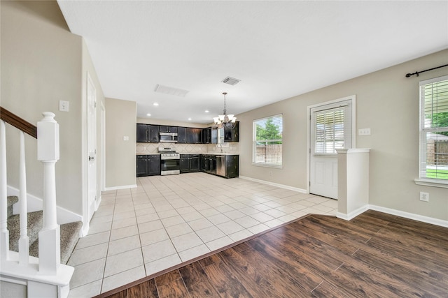32126 Willow Creek Park, Conroe, TX 77385 - kitchen with stainless steel appliances, a chandelier, dark cabinets, decorative backsplash, and healthy amount of natural light
