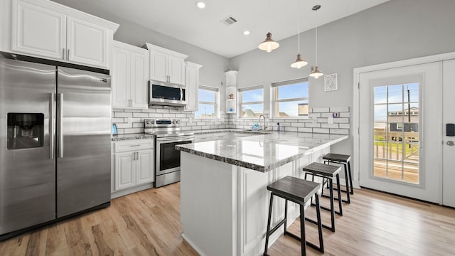 21530 San Luis Pass Rd, Galveston, TX 77554 - kitchen with stainless steel appliances, a sink, white cabinets, a kitchen breakfast bar, and backsplash
