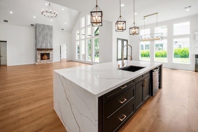 243 Teewood Ct, Montgomery, TX 77356 - kitchen featuring a sink, a chandelier, a stone fireplace, light wood-type flooring, and high vaulted ceiling