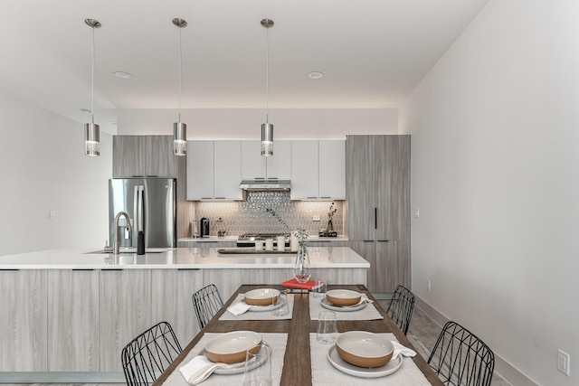 4024 Boho Ln, Houston, TX 77045 - kitchen featuring stainless steel fridge, modern cabinets, tasteful backsplash, under cabinet range hood, and light countertops