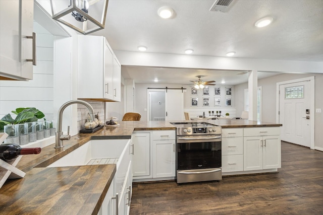 711 S Tesch St, Bellville, TX 77418 - kitchen featuring butcher block counters, stainless steel electric range oven, a peninsula, dark wood-style flooring, and decorative backsplash