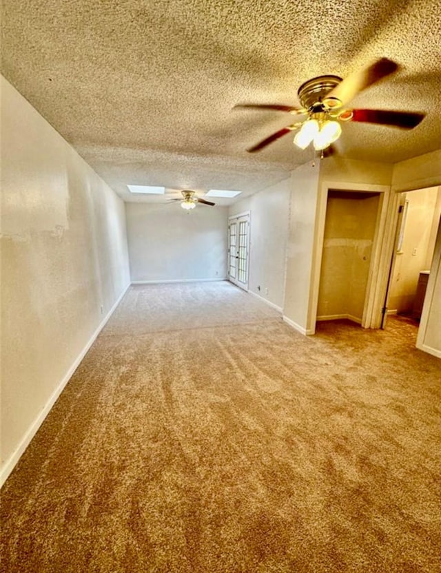 1008 Brockman St, Sweeny, TX 77480 - unfurnished living room featuring carpet flooring, ceiling fan, a skylight, a textured ceiling, and baseboards