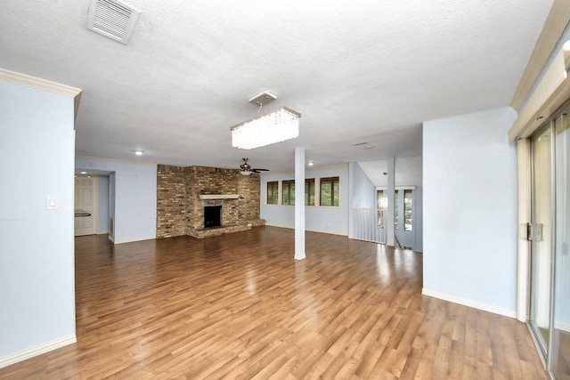 6304 Crab Orchard Rd, Houston, TX 77057 - unfurnished living room featuring a ceiling fan, light wood-type flooring, a textured ceiling, a brick fireplace, and baseboards