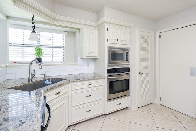 1610 Chapelwood Ln, Richmond, TX 77406 - kitchen featuring appliances with stainless steel finishes, a sink, light tile patterned flooring, light stone counters, and tasteful backsplash