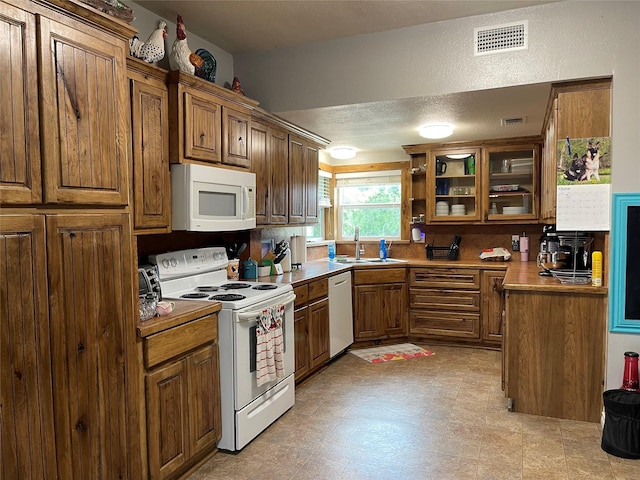 120 N 10th Ave, Teague, TX 75860 - kitchen featuring white appliances, a sink, brown cabinetry, and glass insert cabinets