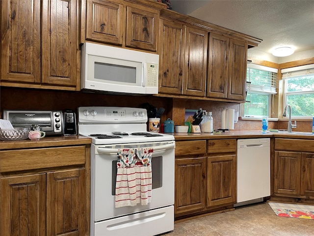 120 N 10th Ave, Teague, TX 75860 - kitchen featuring white appliances, a sink, a textured ceiling, and brown cabinets