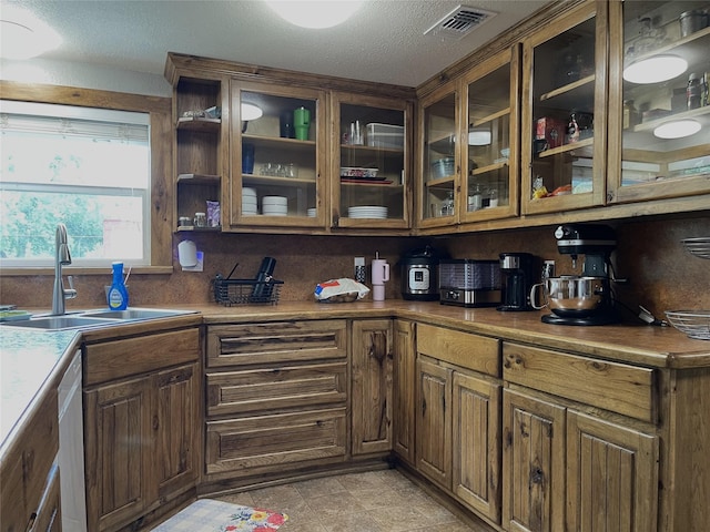 120 N 10th Ave, Teague, TX 75860 - kitchen featuring a sink, glass insert cabinets, a textured ceiling, and stainless steel dishwasher