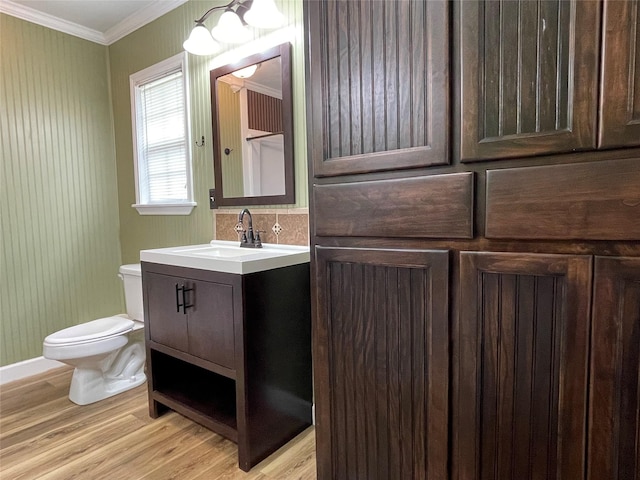 120 N 10th Ave, Teague, TX 75860 - bathroom featuring toilet, vanity, wood finished floors, crown molding, and baseboards