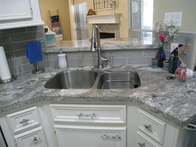 115 Texarkana Dr, Magnolia, TX 77354 - kitchen with a sink, backsplash, white cabinetry, a premium fireplace, and light stone countertops