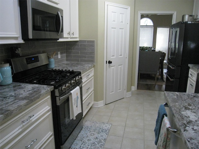 115 Texarkana Dr, Magnolia, TX 77354 - kitchen with range with gas cooktop, stainless steel microwave, freestanding refrigerator, backsplash, and white cabinets