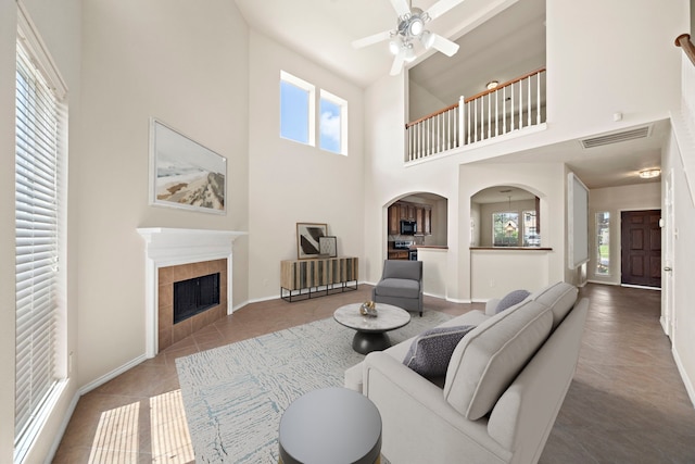 2507 Abernathy Glen Ct, Houston, TX 77014 - living area featuring a towering ceiling, a ceiling fan, a fireplace, arched walkways, and tile patterned flooring