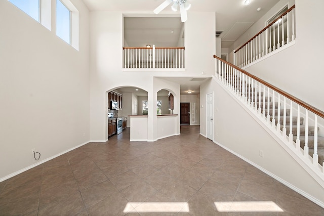 2507 Abernathy Glen Ct, Houston, TX 77014 - unfurnished living room featuring arched walkways, stairs, ceiling fan, tile patterned floors, and a high ceiling