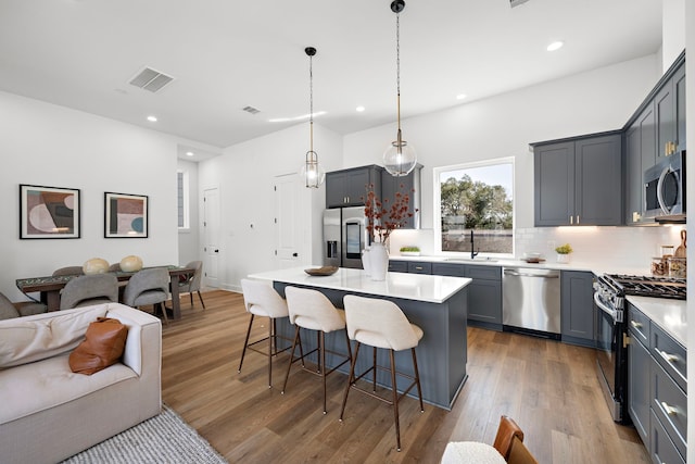 835 Rachel St Unit C, Houston, TX 77091 - kitchen featuring stainless steel appliances, a kitchen breakfast bar, backsplash, wood finished floors, and open floor plan