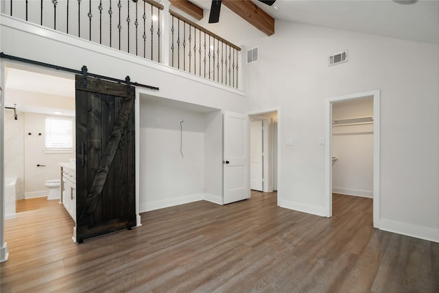 10503 Windriver Dr, Houston, TX 77070 - unfurnished bedroom featuring a barn door, beam ceiling, baseboards, high vaulted ceiling, and wood finished floors