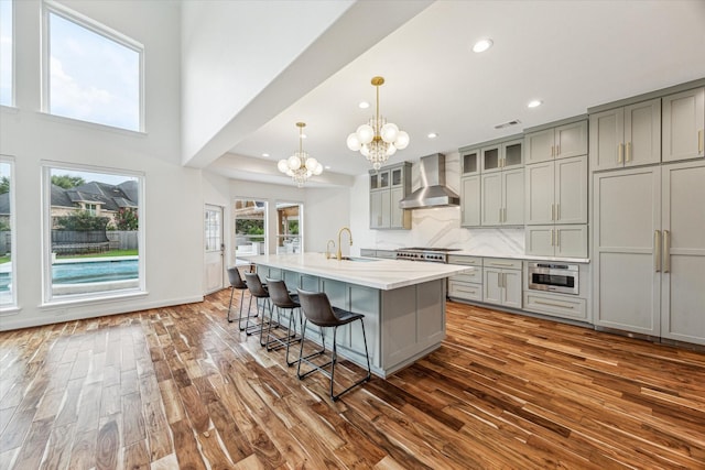 22111 Blacksburg Ct, Katy, TX 77450 - kitchen with wall chimney exhaust hood, gray cabinets, a chandelier, dark wood finished floors, and recessed lighting