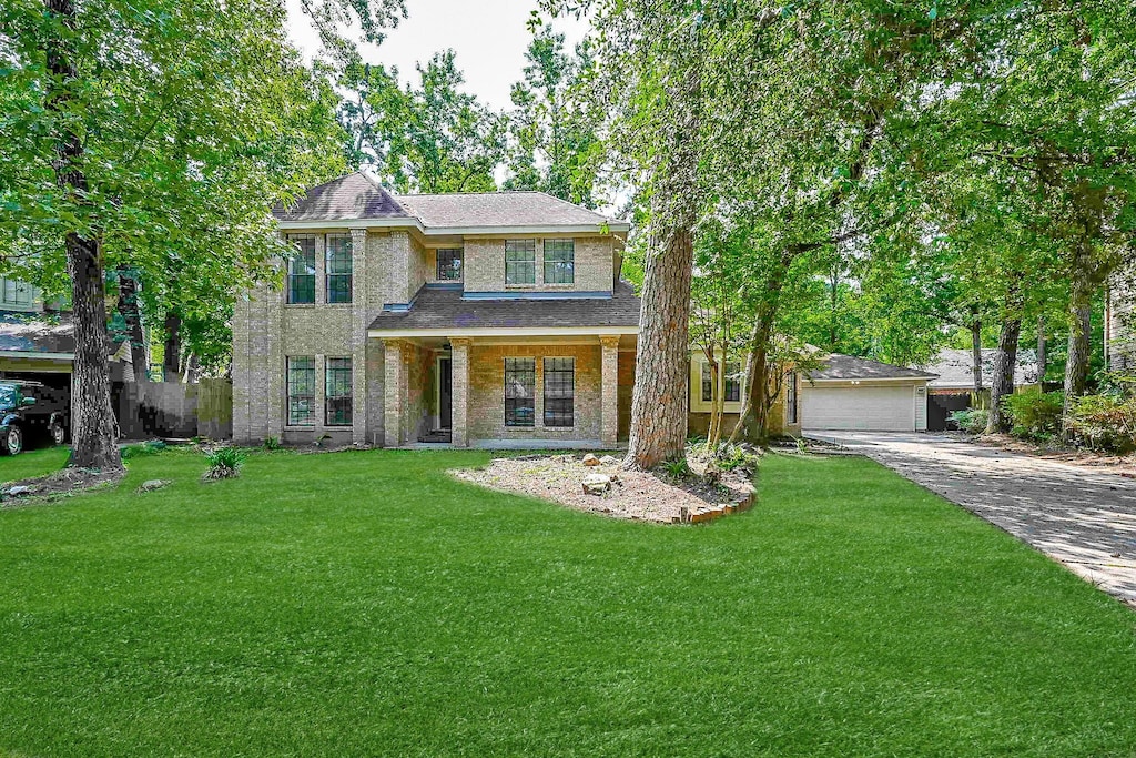 31 Silent Brook Pl, The Woodlands, TX 77381 - view of front of property featuring a front lawn, a garage, driveway, and a shingled roof