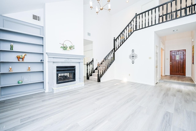 31 Silent Brook Pl, The Woodlands, TX 77381 - unfurnished living room featuring stairway, wood finished floors, a chandelier, a premium fireplace, and a towering ceiling