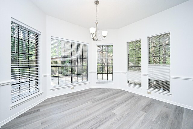 31 Silent Brook Pl, The Woodlands, TX 77381 - unfurnished dining area featuring a chandelier, wood finished floors, and baseboards