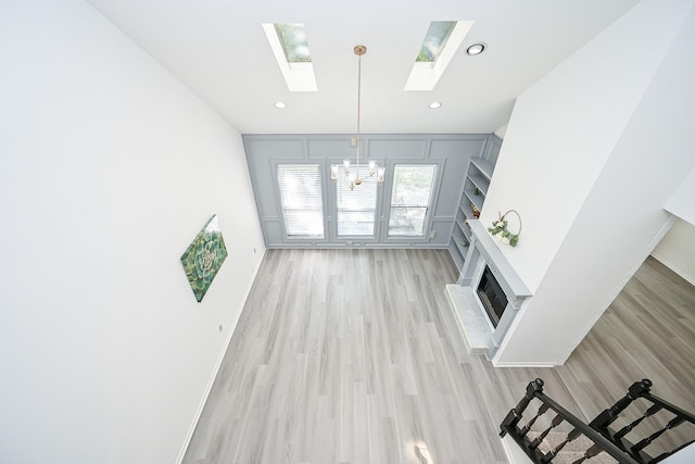 31 Silent Brook Pl, The Woodlands, TX 77381 - unfurnished living room with a chandelier, a skylight, light wood-style floors, a brick fireplace, and recessed lighting